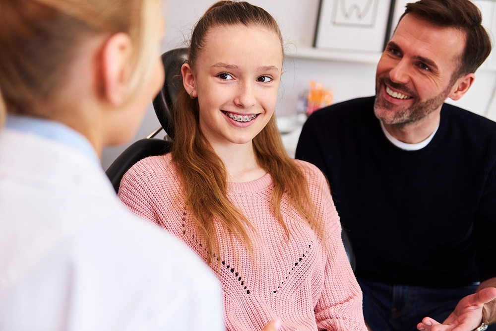 A child with braces and a parent discussing orthodontic care