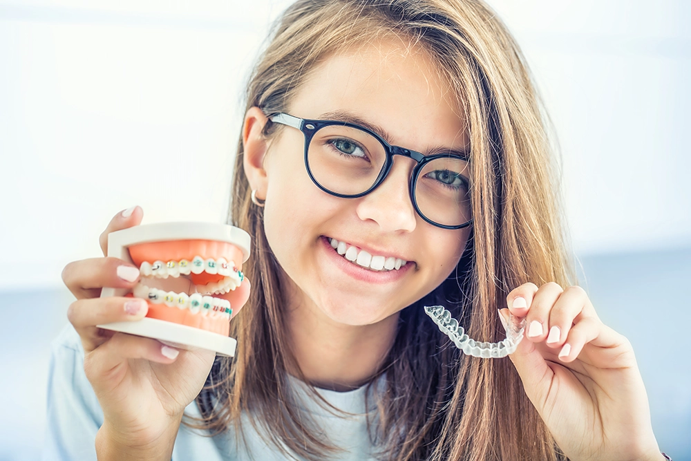 A woman with braces holding a clear orthodontic appliance
